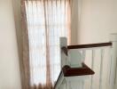 Staircase with wooden handrail and window with curtains