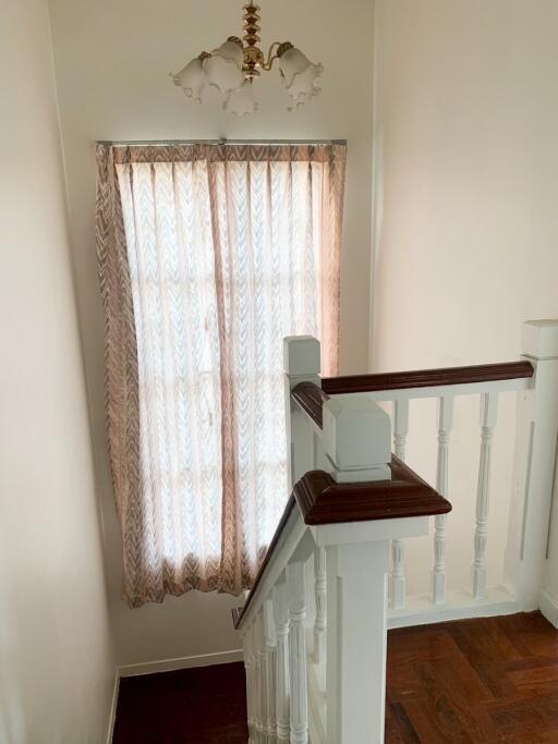 Staircase with wooden handrail and window with curtains