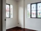 Small bedroom with windows and wooden floor