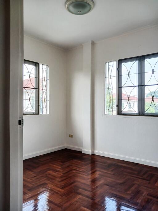 Small bedroom with windows and wooden floor