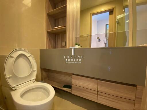 Modern bathroom with open toilet seat, mirror, wooden storage cabinet, and shelves.