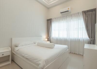 Modern bedroom with white decor, bed, curtains and air conditioning