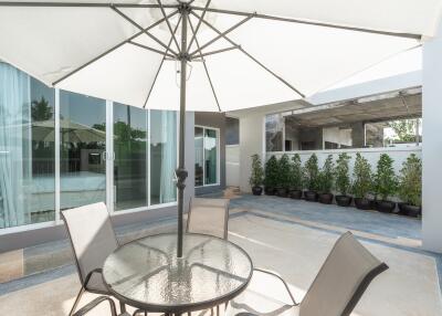 Outdoor patio area with glass table and chairs under an umbrella