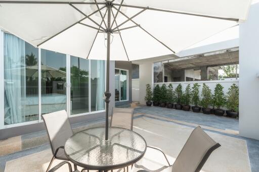 Outdoor patio area with glass table and chairs under an umbrella