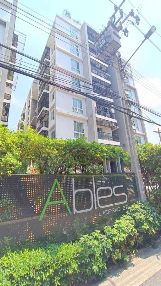 Exterior view of apartment complex with plants and sign reading 