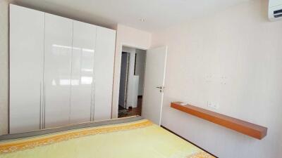 Well-lit bedroom with wardrobe and wall-mounted shelf