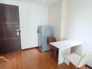 Small dining area with a white table, two chairs, a refrigerator, and a coat rack