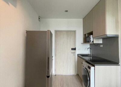 Modern kitchen with fridge, washing machine, and cabinets