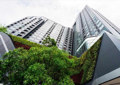 Modern multi-story building with green wall and trees