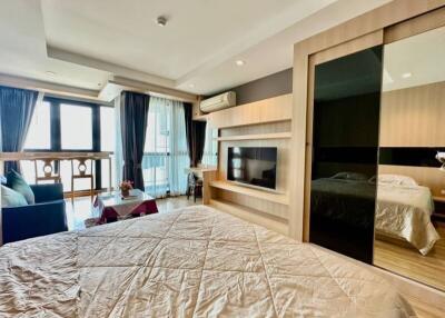 Spacious and modern bedroom with large windows and a separate seating area