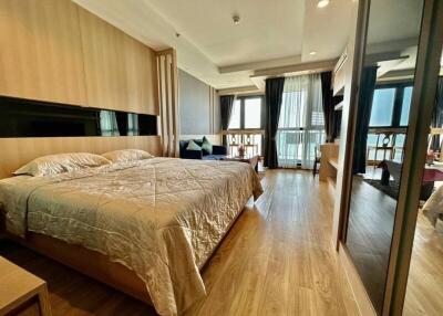 Spacious bedroom with wooden flooring, large bed, and ample natural light
