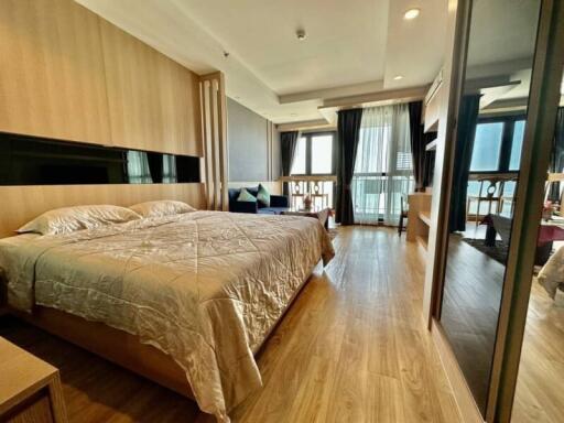 Spacious bedroom with wooden flooring, large bed, and ample natural light