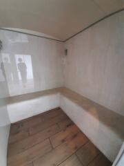 Small enclosed room with wood flooring and tiled walls