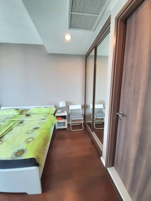 Modern bedroom with green-themed bed and wooden flooring