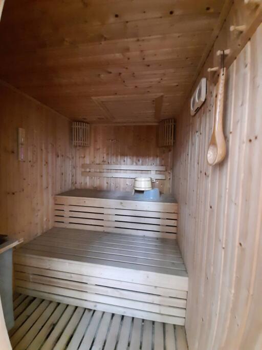 Wooden sauna interior with benches and hanging ladle