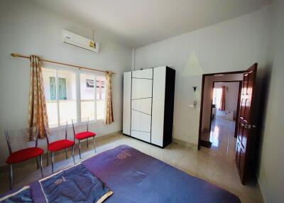 Spacious bedroom with wardrobe, bed, air conditioning, and chairs