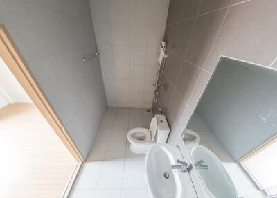 Bathroom with tiled walls and floor, equipped with toilet, sink, and shower