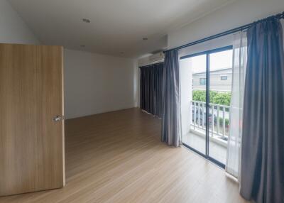 Spacious bedroom with wooden flooring and large window