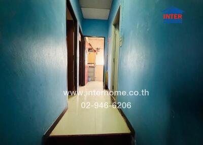 Long hallway with blue walls leading to a kitchen
