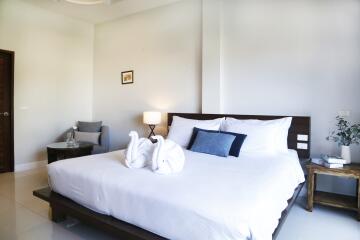 Bedroom with bed, decorative pillows, bedside table, lamp, and sitting area