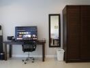 A bedroom with a TV on a desk, chair, wardrobe, mirror, and laundry basket