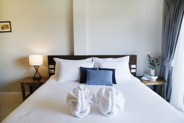 Modern bedroom with a neatly made bed, two bedside tables with lamps, and a large window with curtains