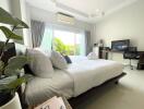 Modern bedroom with a large bed, work desk, and natural light