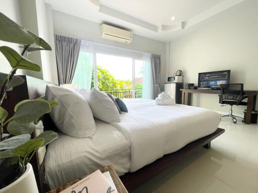 Modern bedroom with a large bed, work desk, and natural light