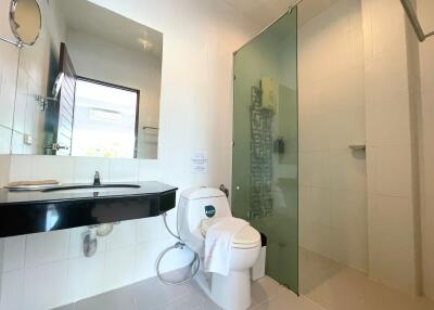 Modern bathroom with large mirror, shower, and toilet