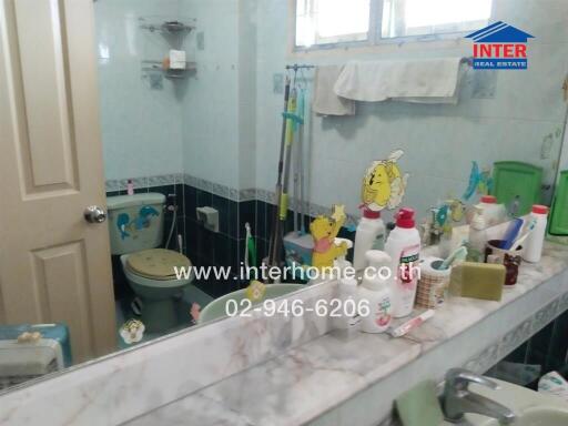 Bathroom with various toiletries on the counter and a mirrored wall