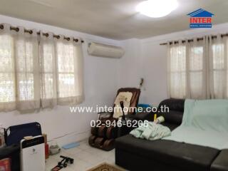 Living room with sofa, wall-mounted air conditioner, and several windows