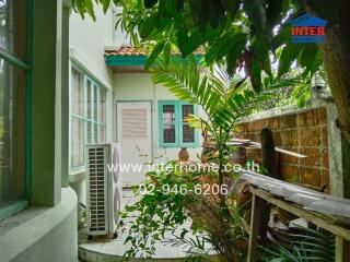 Outdoor patio area with greenery and air conditioning unit