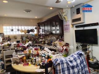 A cluttered kitchen with various items on the countertops and dining table