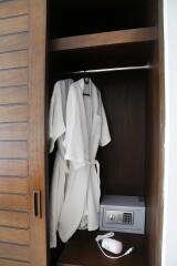 Open closet with robes and a safe