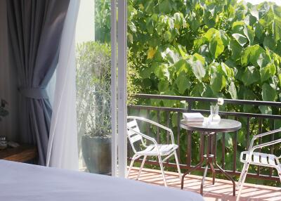 Balcony with a table, chairs, and a view of lush greenery