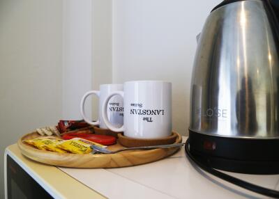 Coffee and tea setup with two mugs, an electric kettle, and snacks