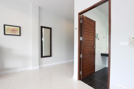 Modern interior with a white wall, a large mirror, and a door leading to a bathroom