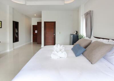 Spacious bedroom with minimalist decor, large bed, and modern amenities