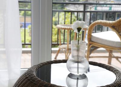 Glass vase with flower on table beside window overlooking outdoor seating