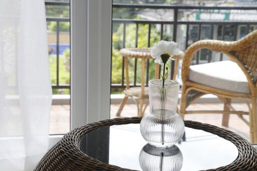 Glass vase with flower on table beside window overlooking outdoor seating
