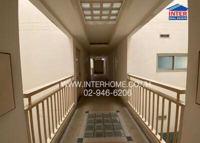 Hallway view with white walls and railing, logo, and contact information.