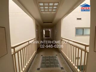 Hallway view with white walls and railing, logo, and contact information.