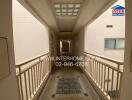 Hallway view with white walls and railing, logo, and contact information.