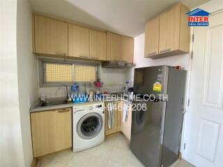 Compact kitchen with wooden cabinets, a washing machine, and a refrigerator