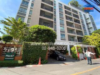 Condominium building exterior with lush greenery and visible signage