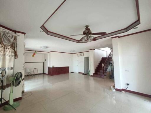 Spacious living room with ceiling fan, staircase, and tiled floor