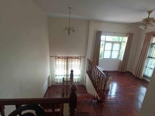 View of a living room with wooden flooring and an upper landing