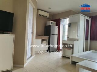 Moderately furnished room with air conditioner, refrigerator, TV, and desk