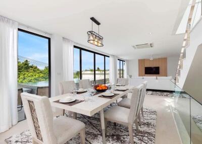 Spacious dining area leading to a living room with large windows and modern decor