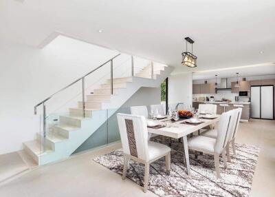 Modern dining area next to staircase with view of the kitchen